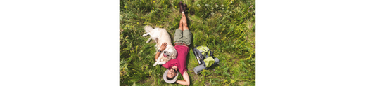 Man relaxing with golden retriever on grassy field, enjoying outdoor freedom with pet